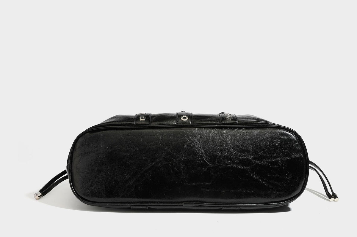 Large black glossy leather-look tote bag with silver buckle straps, eyelet grommet panels, drawstring side gathers, and