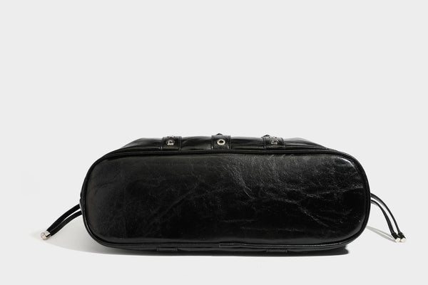 Large black glossy leather-look tote bag with silver buckle straps, eyelet grommet panels, drawstring side gathers, and