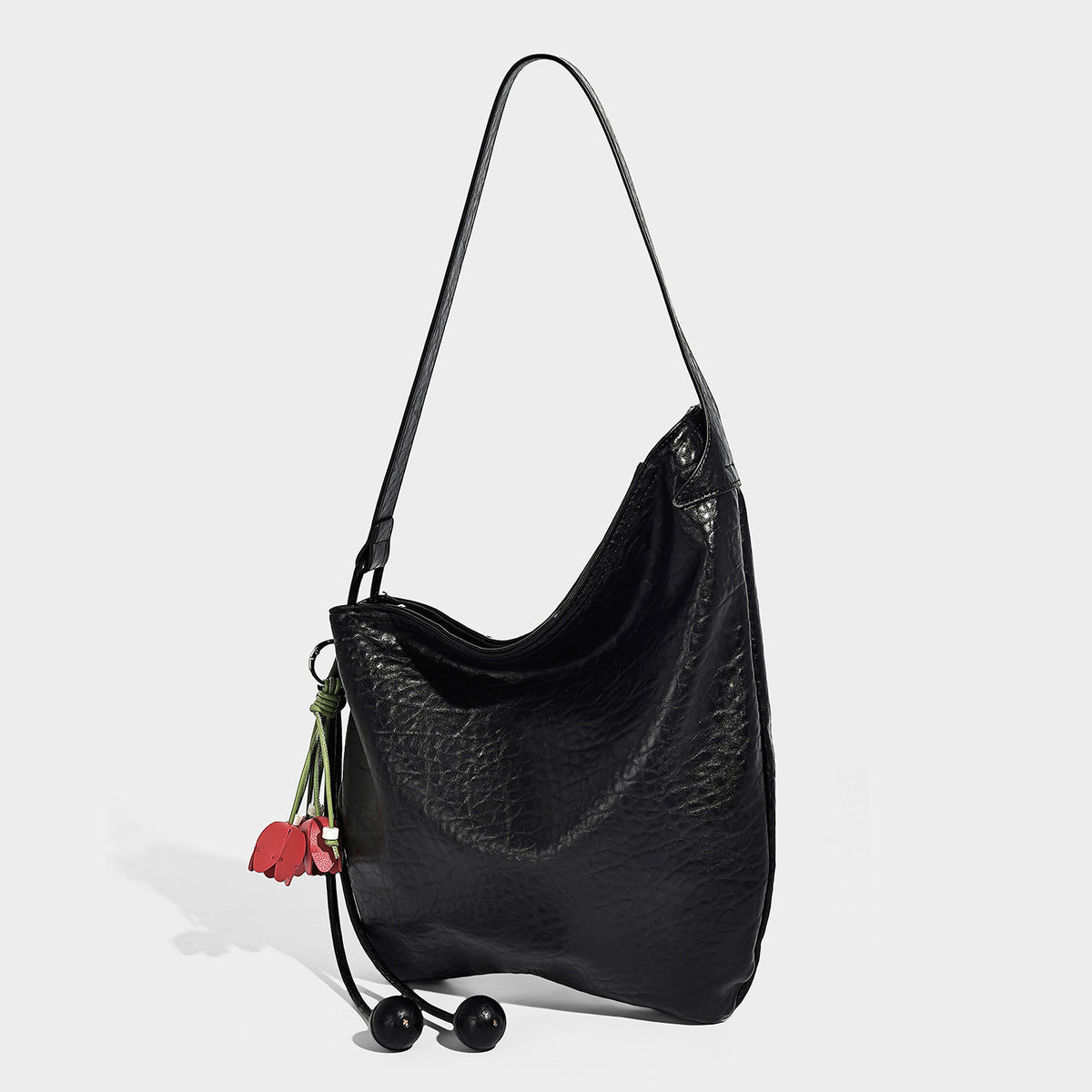 Slouchy hobo shoulder bag in pale yellow with slim strap, drawstring bead closure, and pink tulip floral charm, detail view 6