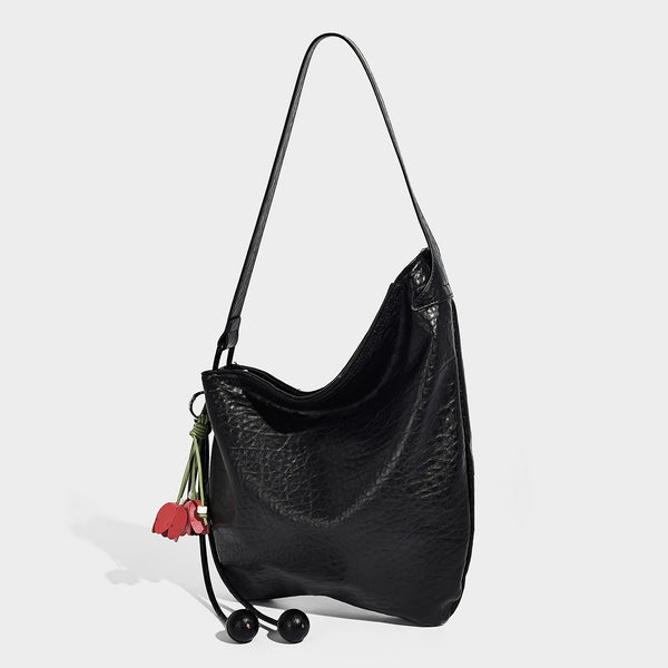 Slouchy hobo shoulder bag in pale yellow with slim strap, drawstring bead closure, and pink tulip floral charm, detail view 6