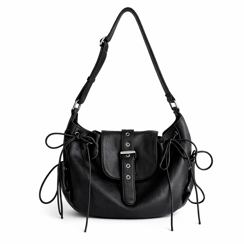 Schwarze Sattelschultertasche in genarbter Lederoptik mit geschnürten Seiteneinsätzen, Ösendetails und Klappe mit silberfarbener Schnalle, Detailansicht