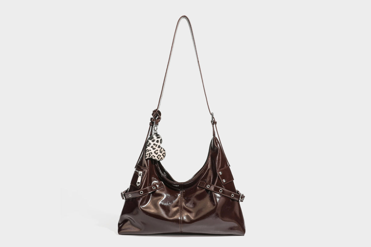 Glänzende dunkelbraune, lässig geschnittene Hobo-Schultertasche mit Riemendetail mit silberfarbenen Ösen, Reißverschlussfach auf der Vorderseite und Herz mit Leopardenmuster