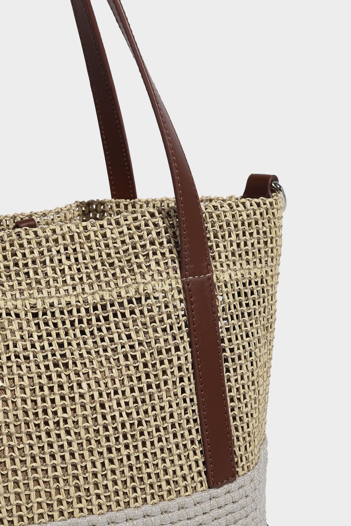 Two-tone open-weave tote bag in beige and cream with brown leather-look handles, tassel bead charm, and detachable
