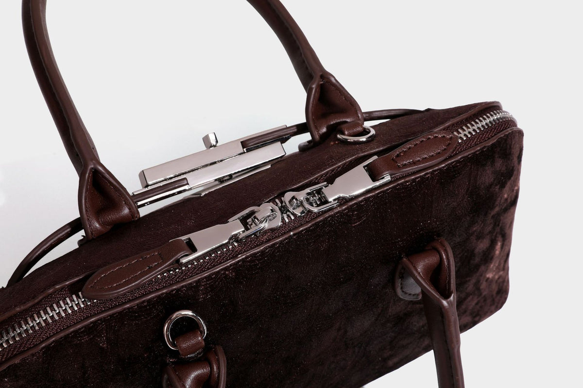 Small structured satchel bag in dark brown velvet-like textured finish with leather-look trim, silver-tone turn-lock bar