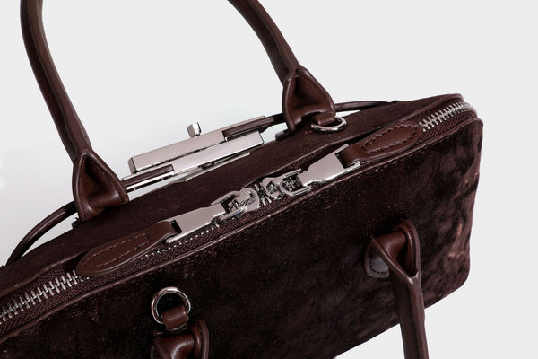 Small structured satchel bag in dark brown velvet-like textured finish with leather-look trim, silver-tone turn-lock bar
