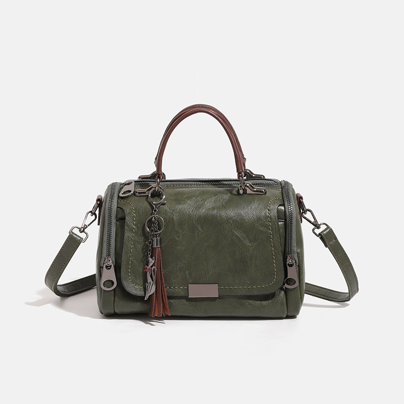 Compact structured barrel bag in distressed leather-look finish with dual top handles, detachable crossbody strap, front zip