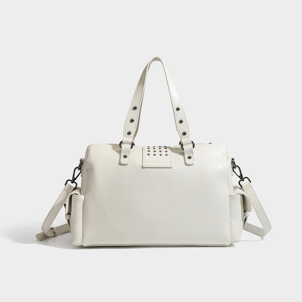 Structured pink leather-look satchel bag with gunmetal studded trim, rectangular buckle strap, dual top handles, and, detail