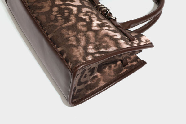 Structured leopard-print tote bag with glossy satin-like finish, dual rounded top handles, silver buckle-and-ring front
