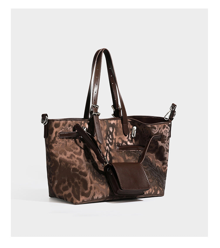 Glossy leopard-print tote bag with leather-look dark trim, dual top handles, detachable shoulder strap, and attached front