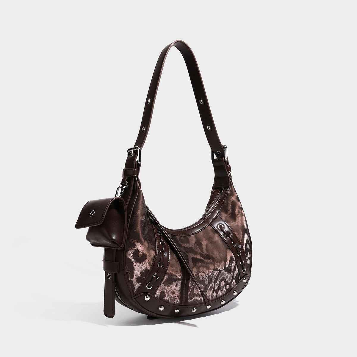 Crescent hobo shoulder bag in brown leopard-print with silver studs, grommet trim, adjustable strap, and detachable mini