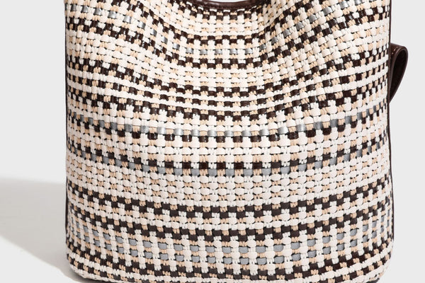 Woven stripe bucket shoulder bag in cream and dark brown with leather-look trim, knotted adjustable strap, and small shield