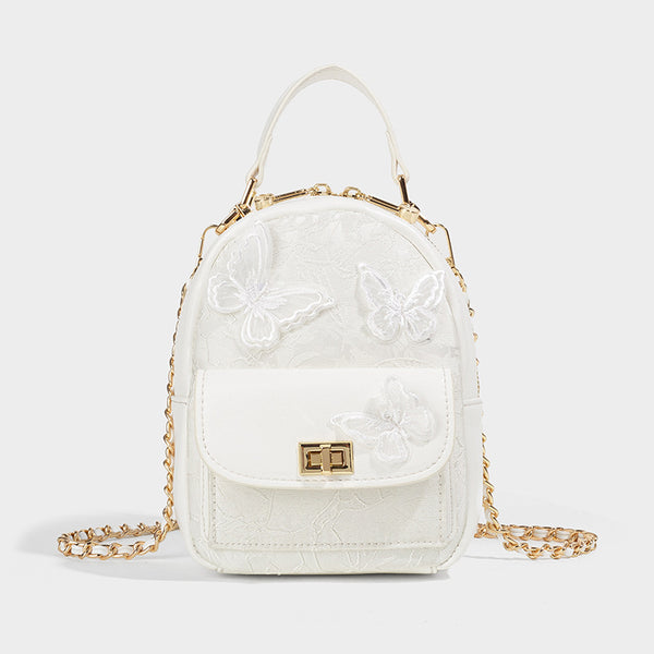 Structured mini backpack handbag with butterfly embroidery, gold-tone chain strap, and turn-lock front flap pocket, detail