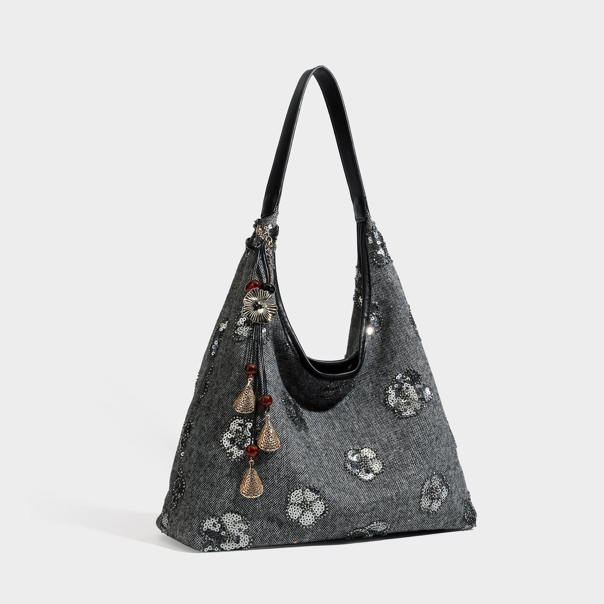 Slouchy trapezoid shoulder tote in charcoal gray with silver sequin floral motifs, leather-look strap, and dangling beaded