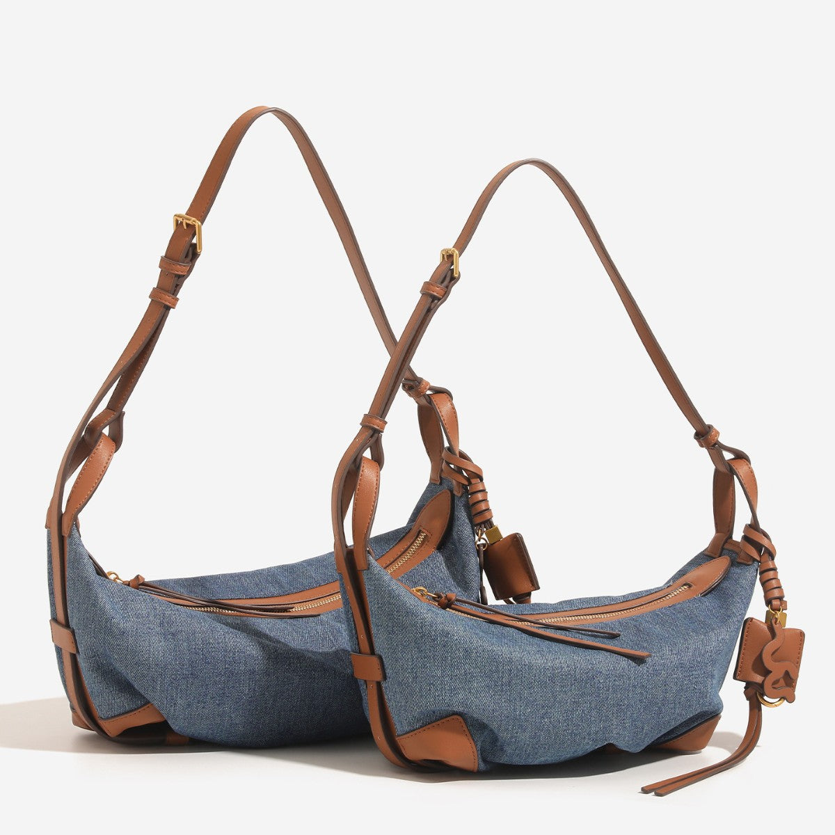 Washed denim canvas crescent hobo bag with tan leather-look trim, knotted strap detail, and gold-tone zipper hardware, front
