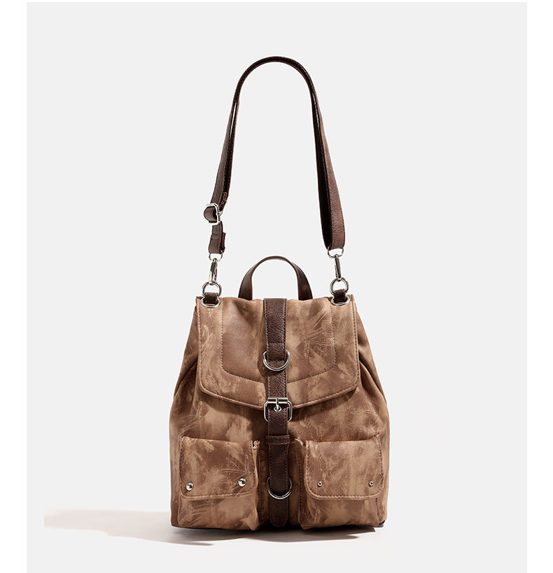 Compact distressed leather-look tan-brown backpack handbag with flap-and-buckle closure, two front patch pockets, top handle