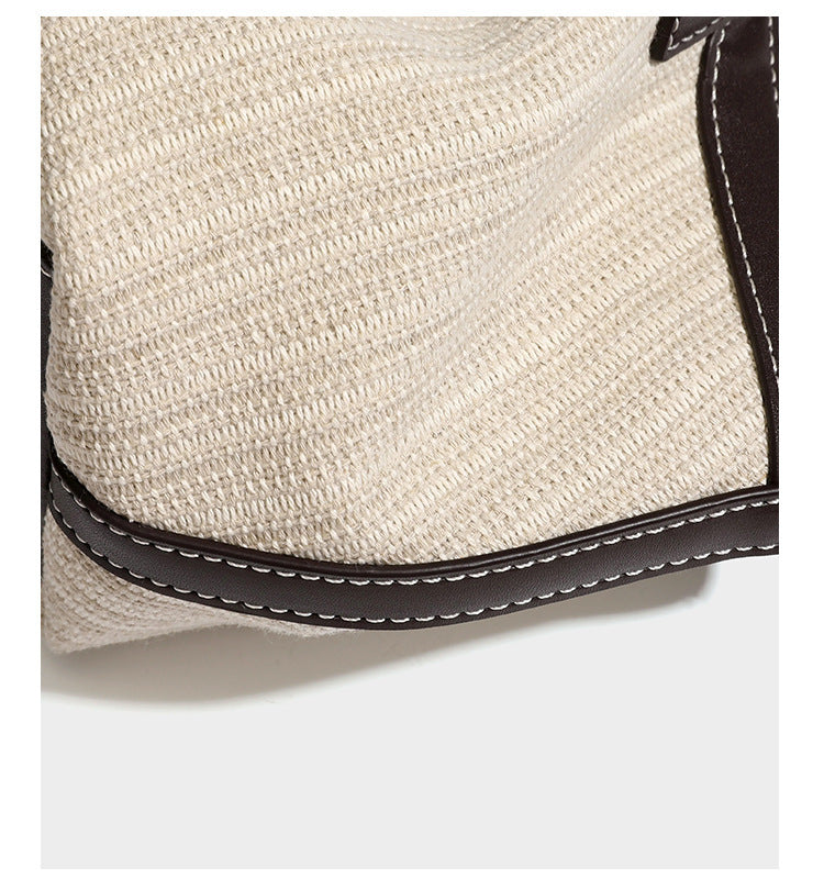 Cremefarbene geflochtene Tote-Bag mit dunkelbraunen Besätzen in Lederoptik, kontrastierenden weißen Nähten, zwei oberen Henkeln und abnehmbarem Schulter