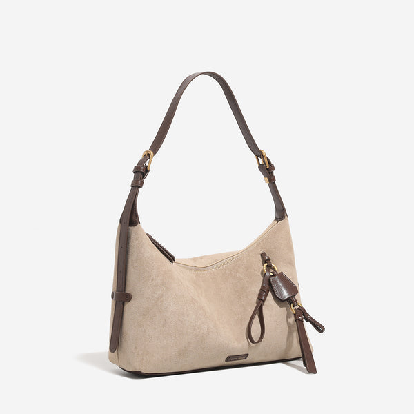 Sand beige slouchy hobo shoulder bag with dark brown trim, adjustable strap, gold-tone hardware, and decorative charm