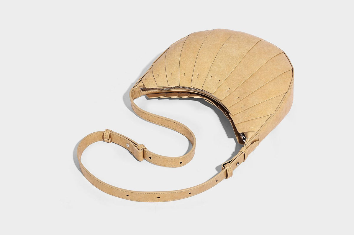 Crescent half-moon shoulder bag with vertical panel seaming, matte-satin leather-look finish, and adjustable gold-tone