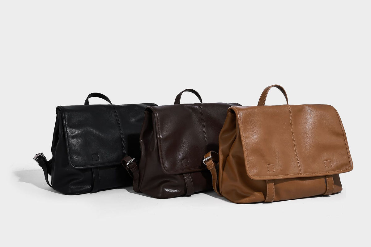 Structured tan leather-look flap backpack handbag with top handle, silver buckle hardware, and fold-over front closure