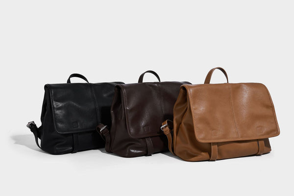 Structured tan leather-look flap backpack handbag with top handle, silver buckle hardware, and fold-over front closure