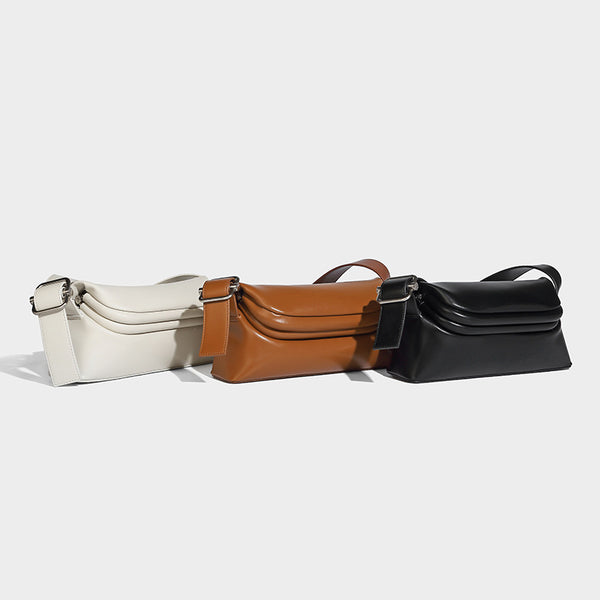 Compact structured baguette shoulder bag with smooth leather-look finish, zip top, and adjustable silver-buckle strap, detail