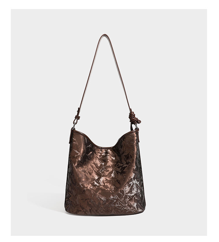Große Hobo-Schultertasche mit Knitterglanz in Dunkelbraun, schmalem verstellbarem Riemen, geknoteten Metalldetails und seitlich angesetzter Klappe