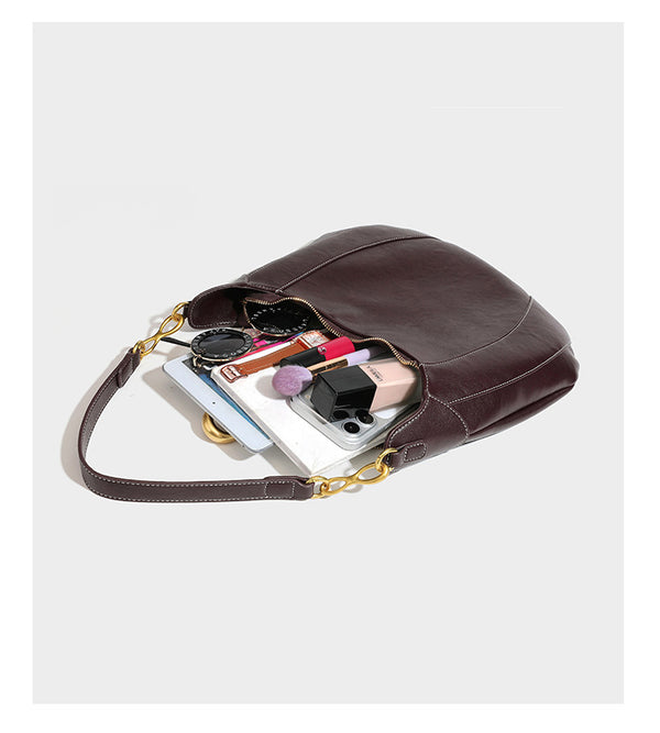 Locker fallende Hobo-Schultertasche in Halbmondform in Dunkelbraun mit goldfarbenem Ring und Kettenglied-Details sowie Reißverschluss oben, Detailansicht