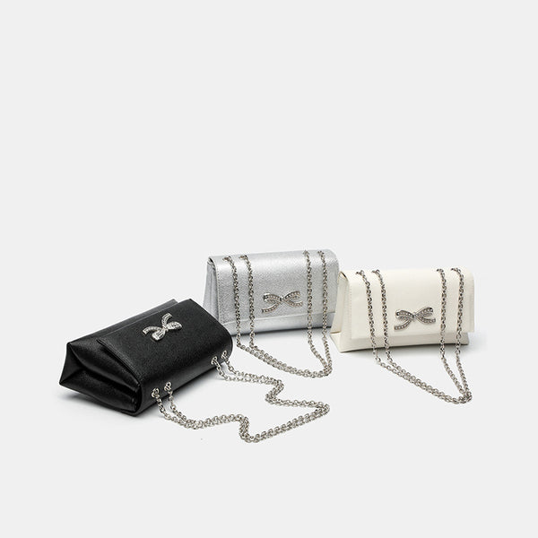 Structured rectangular flap crossbody bag with rhinestone bow and silver chain strap in pebbled finish, detail view 2