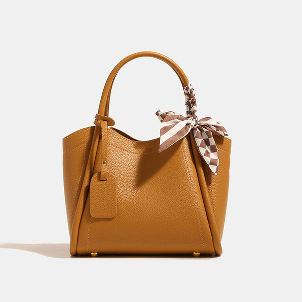Structured pebbled tote bucket bag in apricot with braided top handle, checkered bow scarf, gold-tone hardware, and, detail