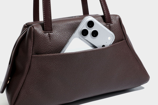 Structured trapezoid shoulder bag in dark brown pebbled leather-look finish with slim double straps, top zip closure, side