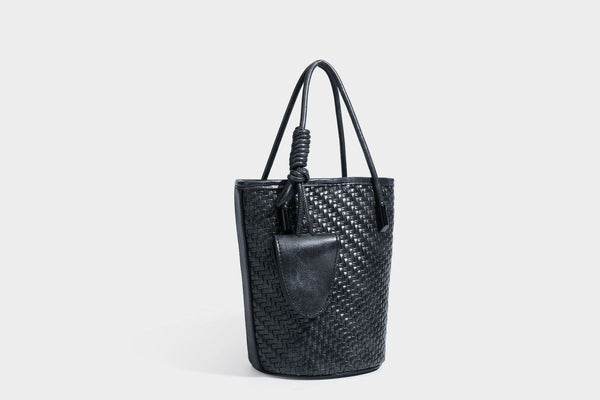 Structured woven-texture leather-look bucket bag in brown with knotted top handles, small front flap pouch, and adjustable