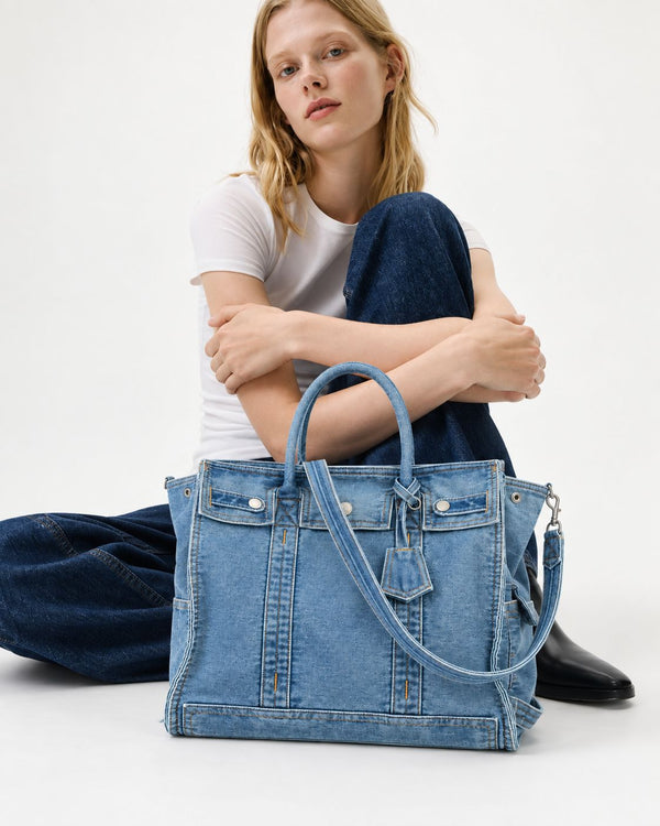 Large washed denim patchwork tote bag with snap-flap front pockets, rolled handles, and detachable shoulder strap, detail