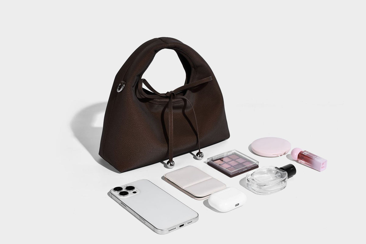Pebbled matte trapezoid top-handle bag with drawstring bow closure, bead-tipped cords, silver-tone hardware, and detachable