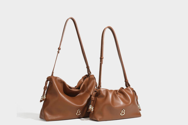Slouchy ruched drawstring shoulder bag in smooth leather-look finish with gold-tone emblem and slim adjustable strap, detail