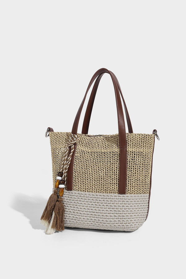 Two-tone open-weave tote bag in beige and cream with brown leather-look handles, tassel bead charm, and detachable
