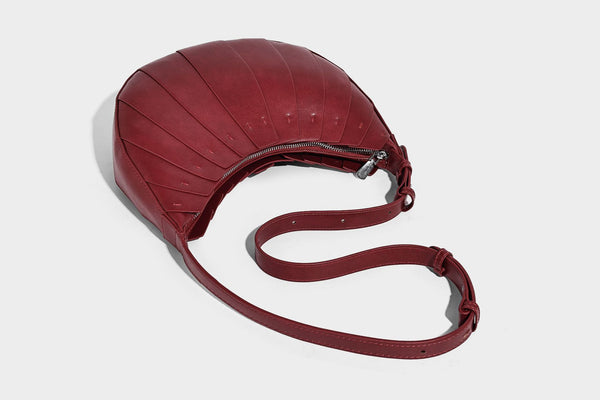 Crescent half-moon shoulder bag with vertical panel seaming, matte-satin leather-look finish, and adjustable gold-tone