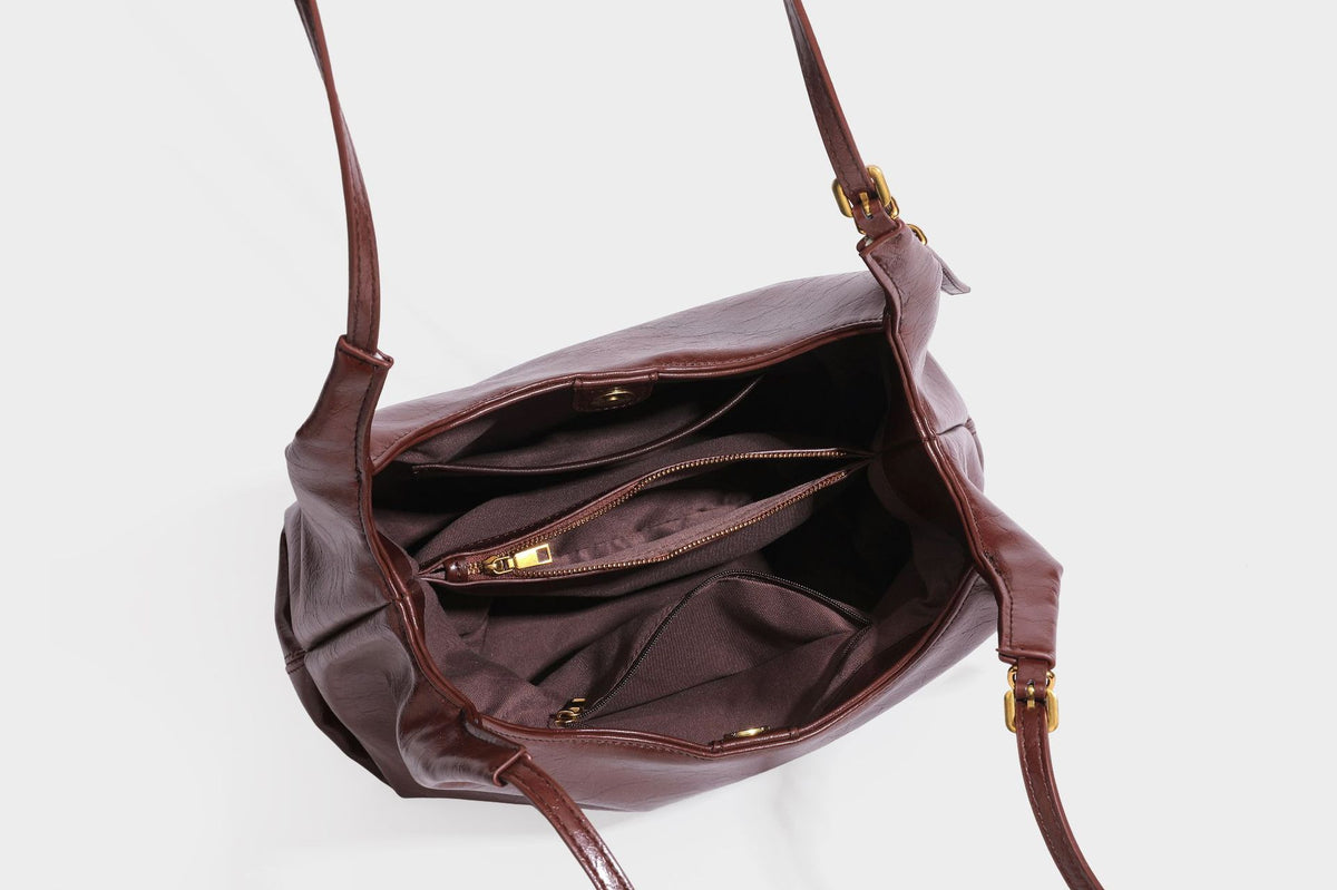 Locker fallende Hobo-Schultertasche mit offenem Oberteil aus glänzendem, geknautschtem Lederimitat in Dunkelbraun, mit schmalem verstellbarem Riemen und goldfarbenem