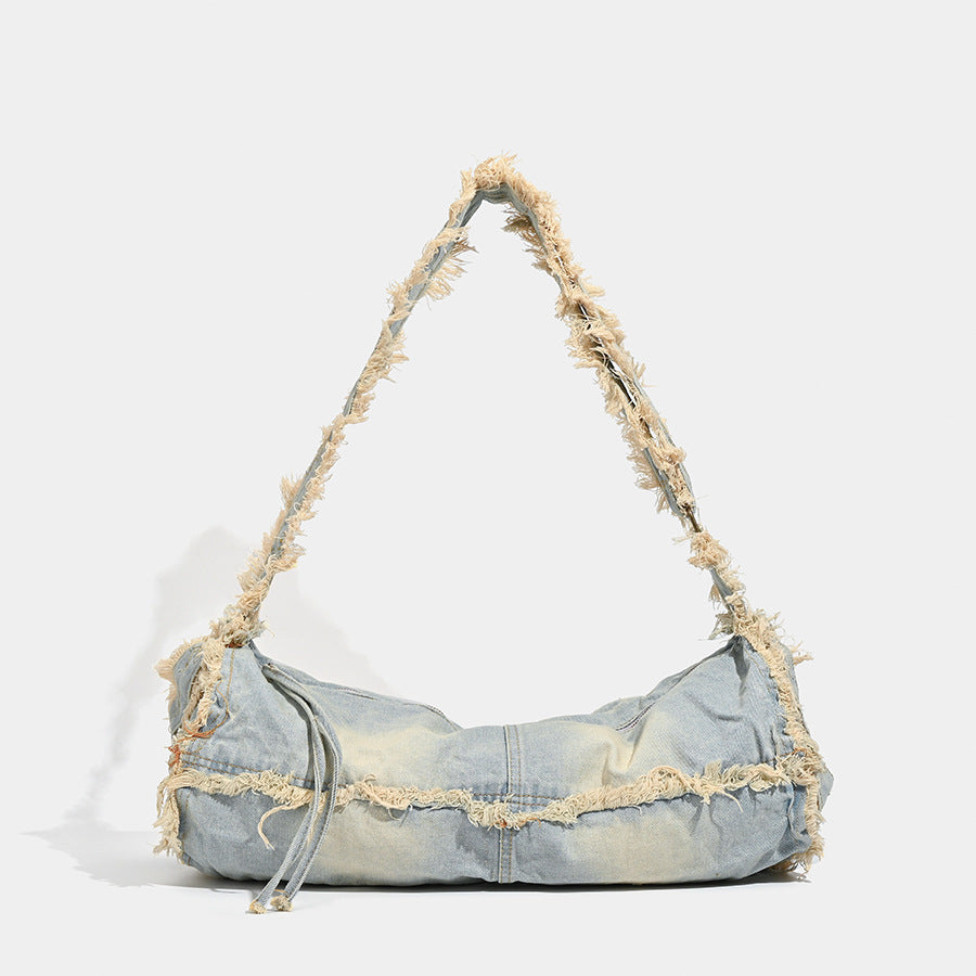 Large slouchy washed denim shoulder bag with frayed raw-edge trim and zip-top closure, detail view 6
