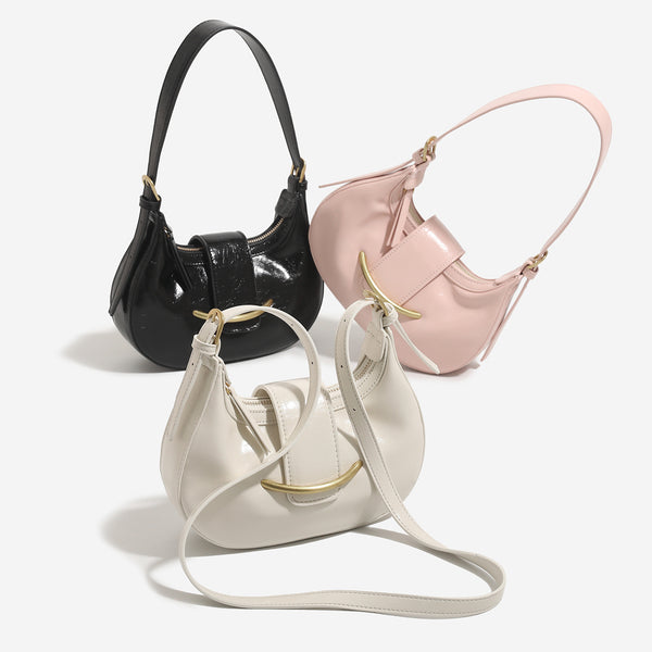 Compact crescent hobo shoulder bag with glossy synthetic finish, curved gold-tone front bar hardware, zip-top closure, and