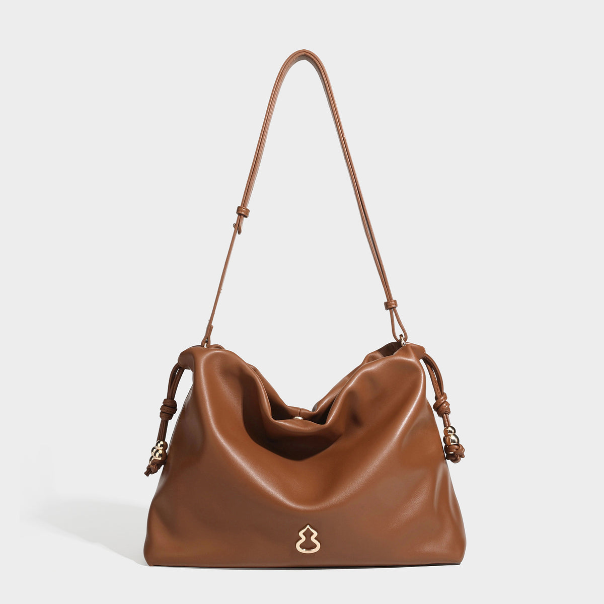 Slouchy ruched drawstring shoulder bag in smooth leather-look finish with gold-tone emblem and slim adjustable strap, detail