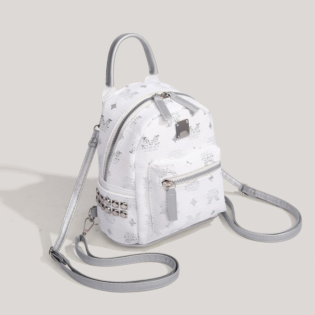 Kleiner strukturierter silberfarbener Mini-Rucksack in Kuppelform mit genarbter Prägeoptik, Beschlägen in Silberoptik, Tragegriff und vorderer Reißverschlusstasche