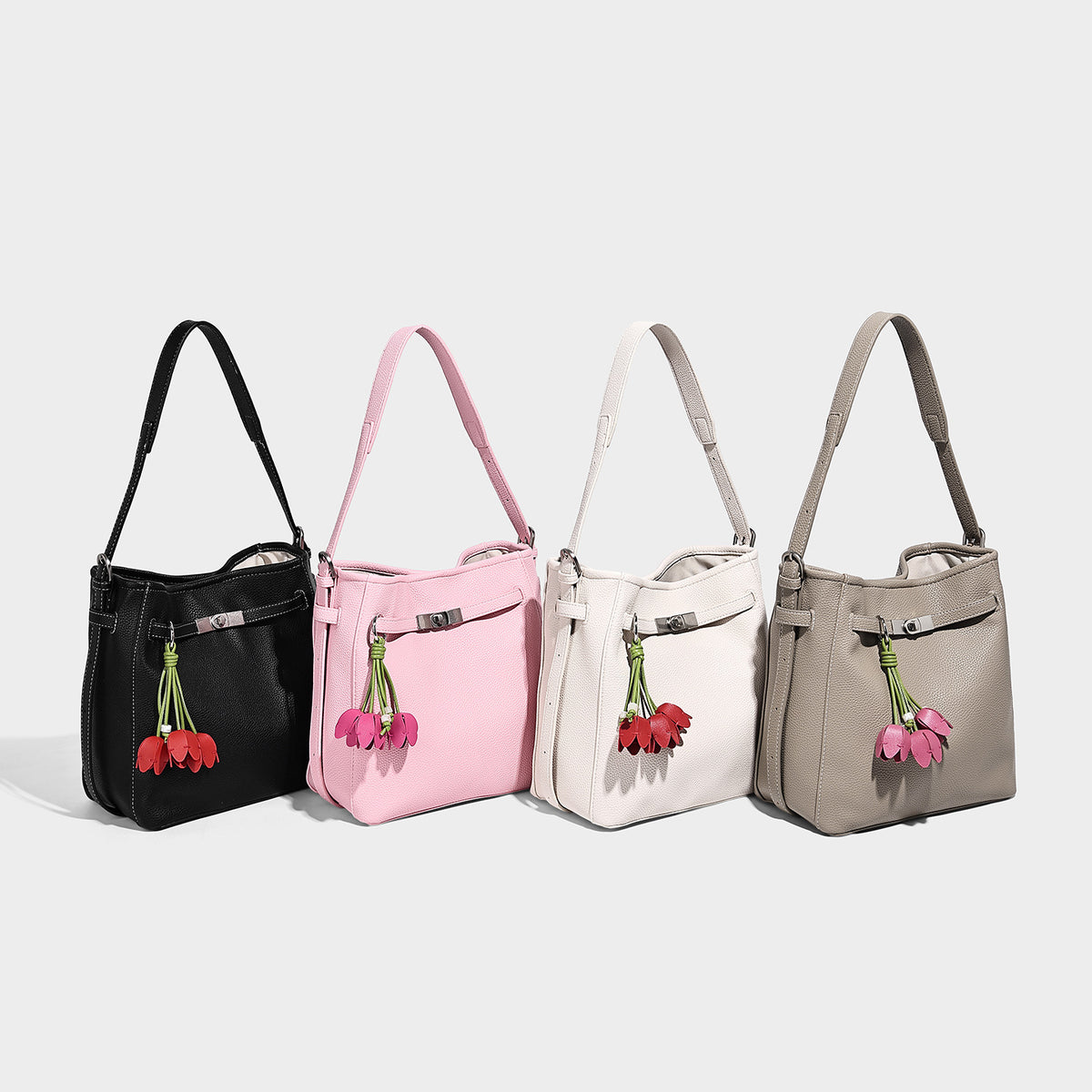 Soft-structured pebbled bucket shoulder bag with front turn-lock strap detail, adjustable strap, and hanging floral tassel