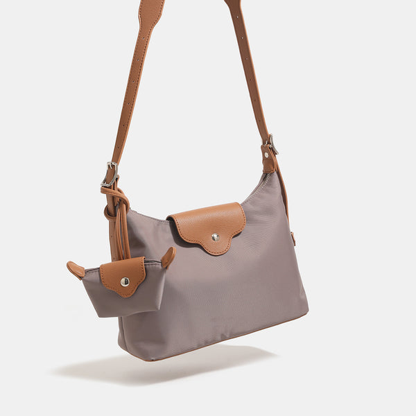 Slouchy hobo shoulder bag in smooth fabric with leather-look tan trim, zip-top closure, adjustable strap, and detachable