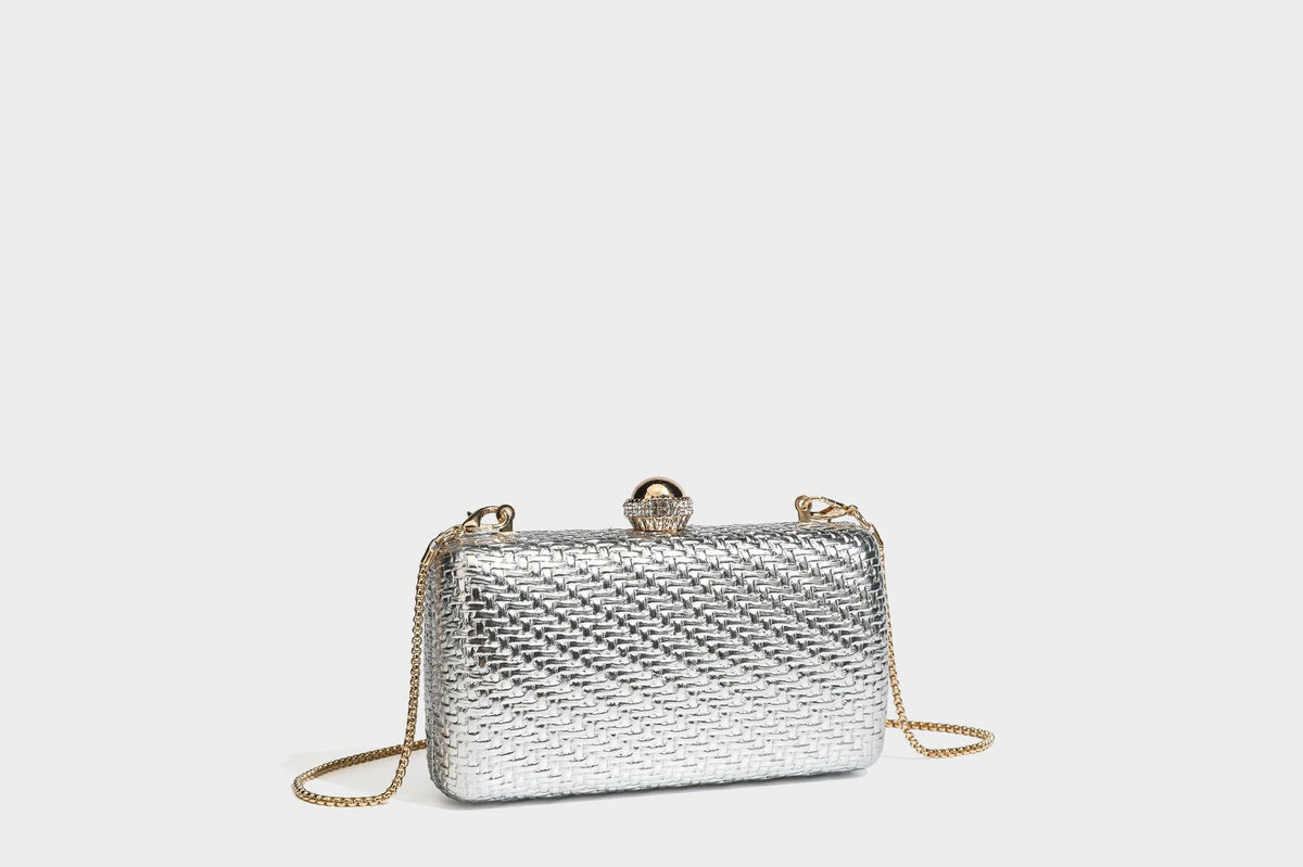 Small structured metallic woven-texture box clutch bag with jeweled kiss-lock dome clasp and slim gold chain strap, detail