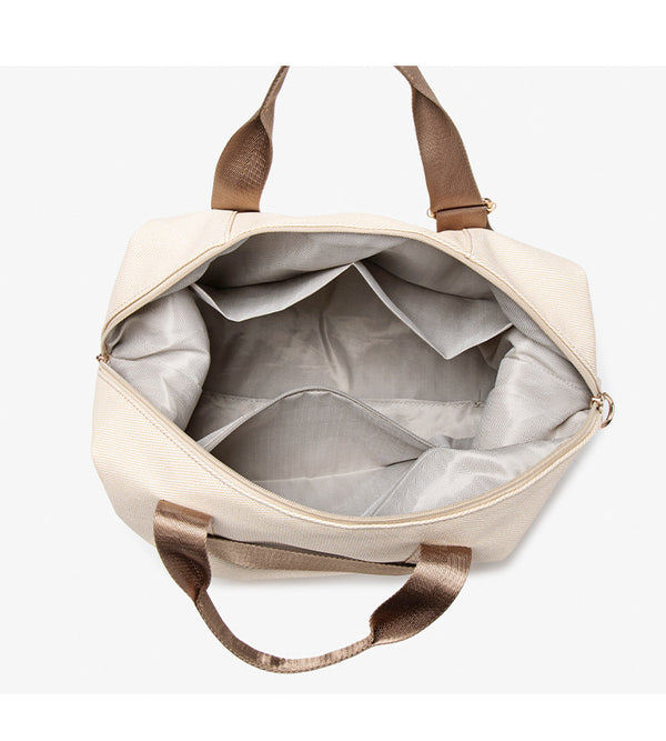 Structured woven duffel bag with dual tan webbing handles, detachable shoulder strap, top zip closure, and gold-tone