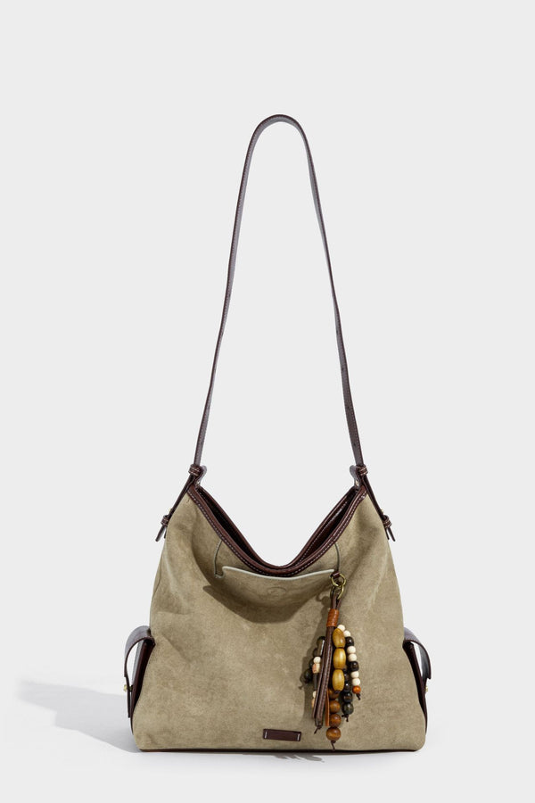 Lässig fallende Hobo-Schultertasche in Khaki aus mattem Material in Wildlederoptik mit dunkelbraunem Besatz in Lederoptik, Quastenanhänger mit Perlen und seitlicher Klappe, Detailansicht