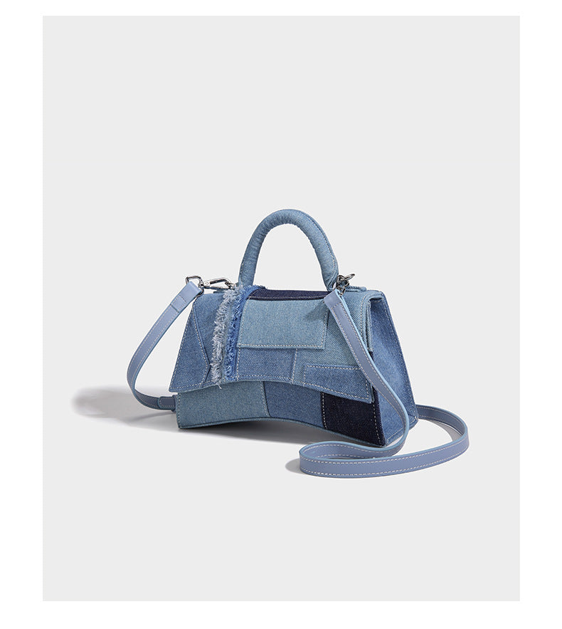 Structured patchwork denim trapezoid satchel bag with frayed panel trim, rounded top handle, and silver-tone hardware, detail