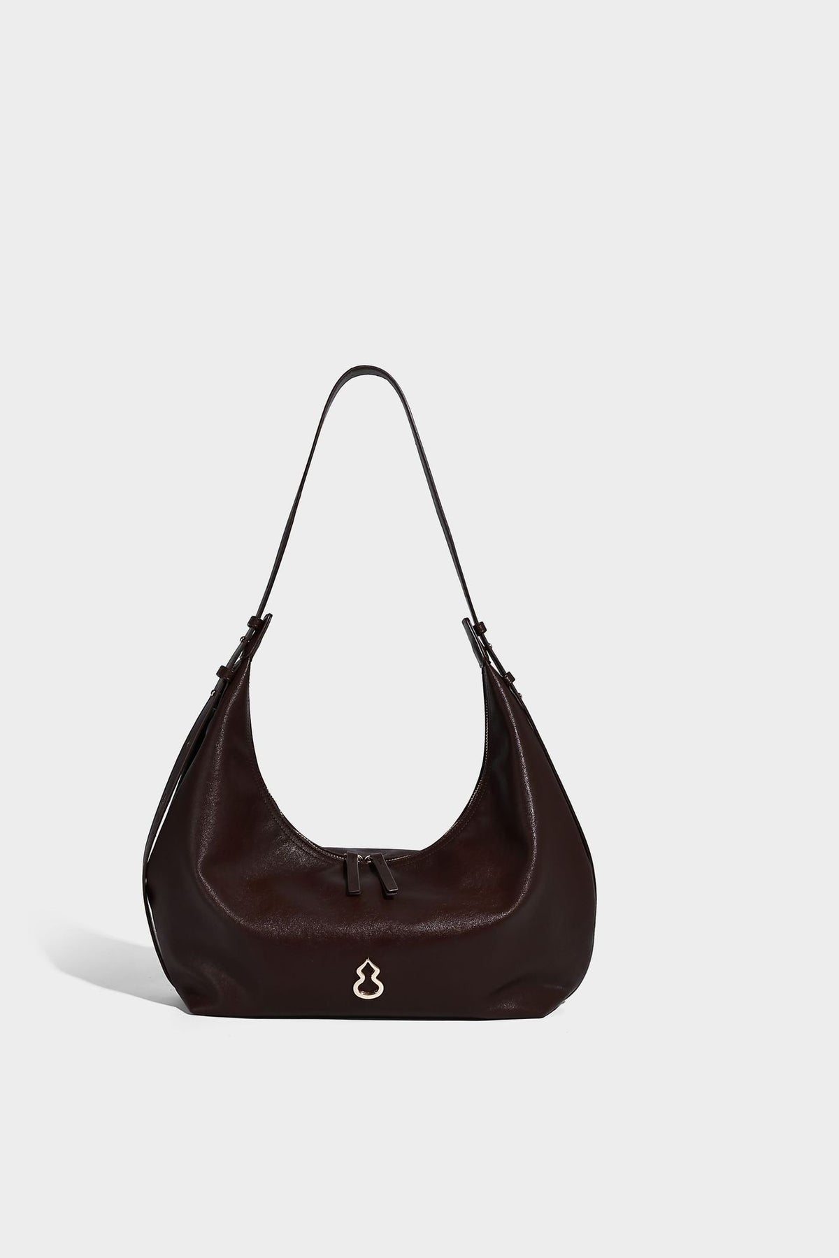 Lässig fallende, sichelförmige Hobo-Schultertasche in glatter dunkelbrauner Lederoptik mit Logo-Anhänger in Goldoptik und verstellbarem Schulterriemen