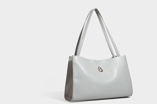 Structured rectangular shoulder tote bag with smooth leather-look finish, long double straps, and gold-tone gourd emblem on