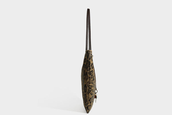 Large leopard print shoulder tote bag in tan and brown with slim dark straps and dangling beaded charm hardware, detail view